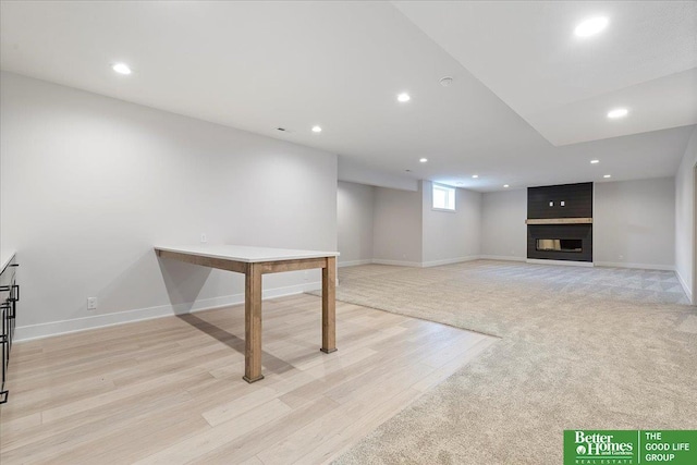 basement featuring light wood-style floors, recessed lighting, baseboards, and a large fireplace