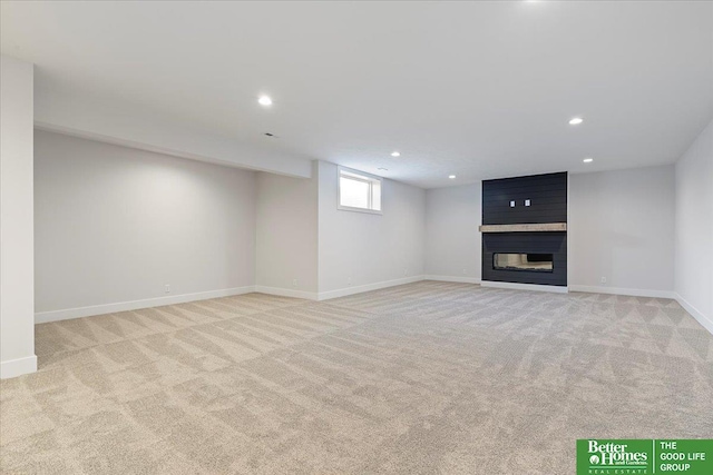 basement featuring light carpet, recessed lighting, a fireplace, and baseboards