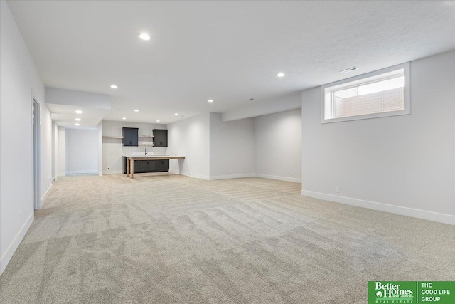 unfurnished living room with recessed lighting, baseboards, and light carpet
