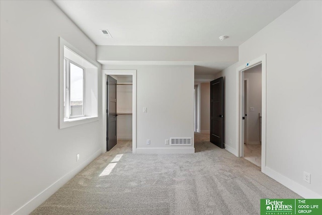 unfurnished bedroom featuring carpet flooring, a spacious closet, and baseboards