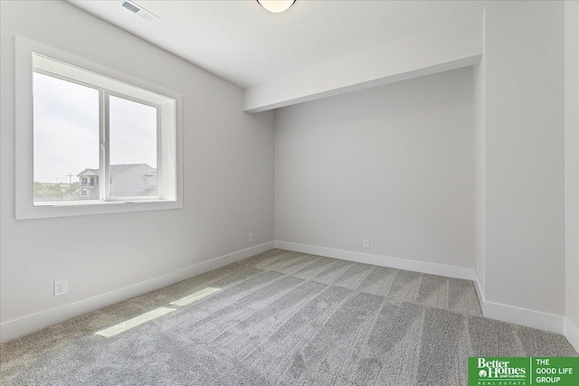 spare room featuring light colored carpet and baseboards