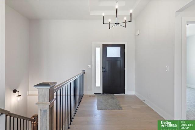 foyer with a chandelier, light wood-style floors, and baseboards