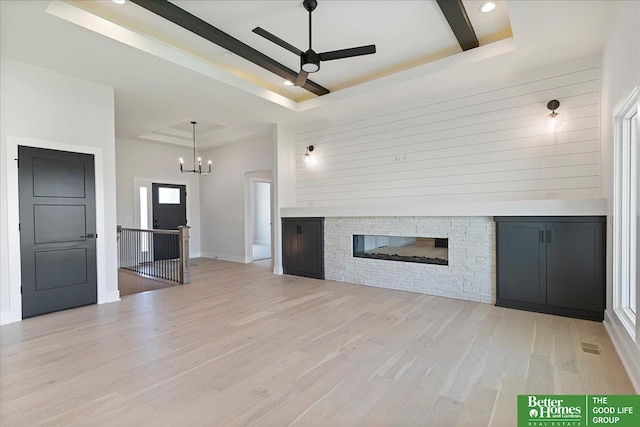 unfurnished living room with a tray ceiling, a ceiling fan, a fireplace, light wood-style flooring, and recessed lighting