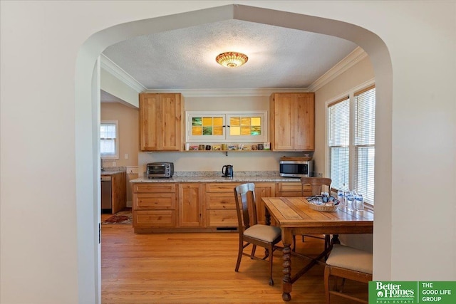 kitchen featuring arched walkways, ornamental molding, stainless steel appliances, plenty of natural light, and a textured ceiling