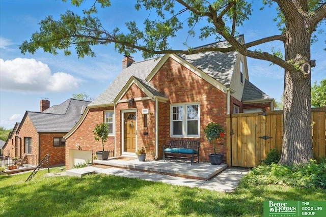 view of front of property with brick siding, a chimney, roof with shingles, a gate, and an attached garage