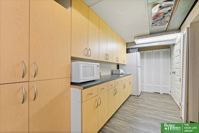 kitchen featuring white appliances, light wood-style flooring, and dark countertops