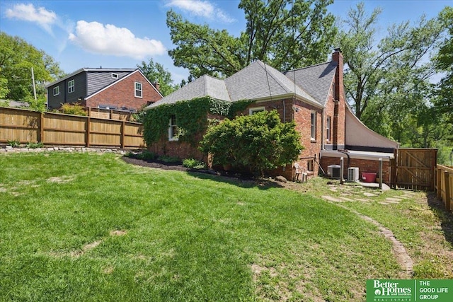view of home's exterior featuring a chimney, brick siding, central AC, and roof with shingles