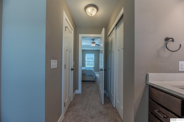 hall featuring light colored carpet and baseboards