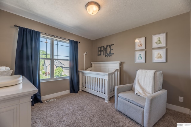 bedroom featuring light colored carpet, baseboards, a textured ceiling, and a nursery area