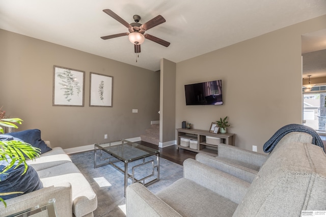 living room with ceiling fan, wood finished floors, baseboards, and stairway