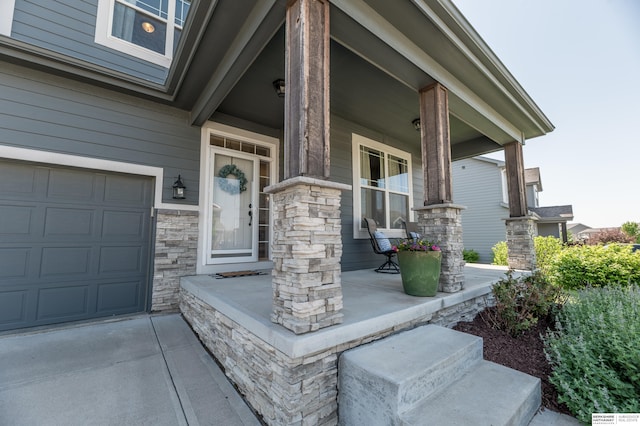 property entrance featuring covered porch, stone siding, and a garage
