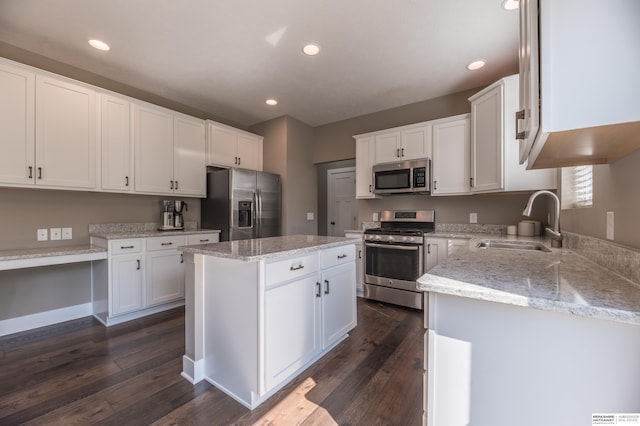 kitchen featuring appliances with stainless steel finishes, a sink, white cabinets, dark wood-style flooring, and a kitchen island