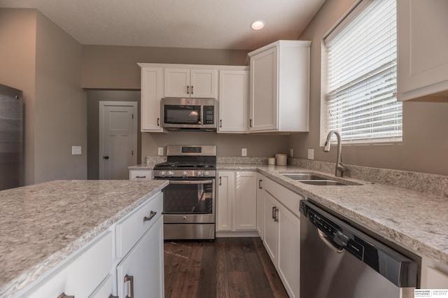 kitchen featuring appliances with stainless steel finishes, a sink, dark wood-type flooring, white cabinets, and recessed lighting