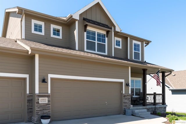 craftsman-style home with an attached garage, stone siding, board and batten siding, and a shingled roof