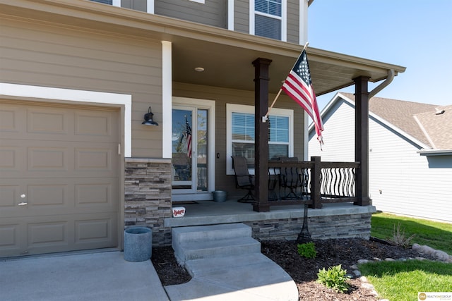 entrance to property featuring covered porch, a garage, and stone siding
