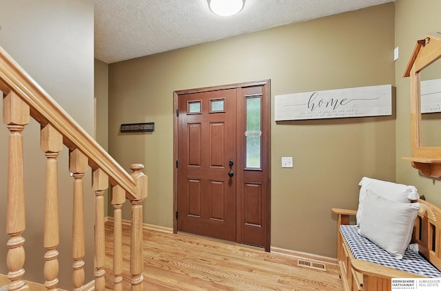 2103 John St, Papillion, NE 68133 - foyer entrance with light wood-type flooring, a textured ceiling, stairs, and baseboards