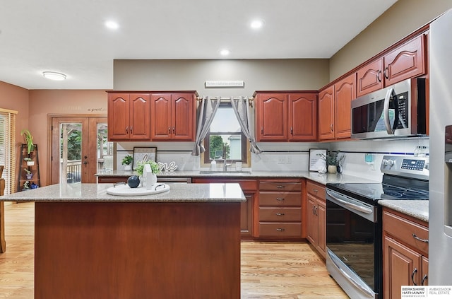 2103 John St, Papillion, NE 68133 - kitchen with stainless steel appliances, a sink, light wood-style floors, a center island, and recessed lighting