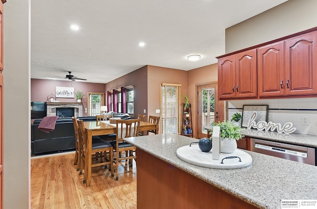 2103 John St, Papillion, NE 68133 - kitchen with light wood-style floors, stainless steel dishwasher, a ceiling fan, a fireplace, and recessed lighting