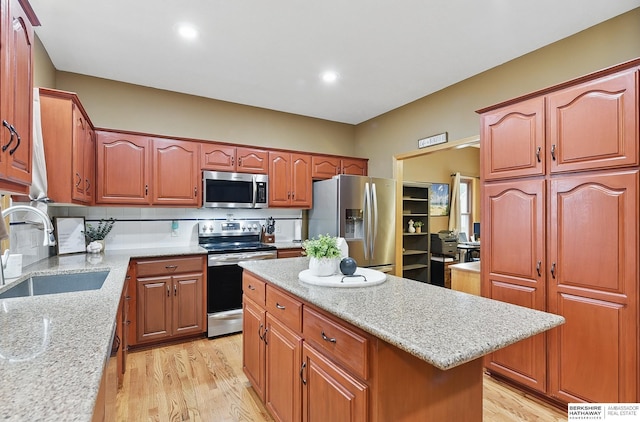 2103 John St, Papillion, NE 68133 - kitchen featuring a sink, appliances with stainless steel finishes, light wood-type flooring, a kitchen island, and light stone counters