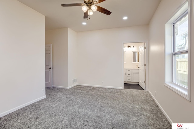 unfurnished bedroom with dark carpet, baseboards, recessed lighting, connected bathroom, and ceiling fan