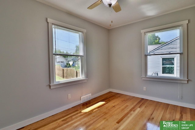 empty room featuring plenty of natural light, baseboards, wood finished floors, ceiling fan, and crown molding
