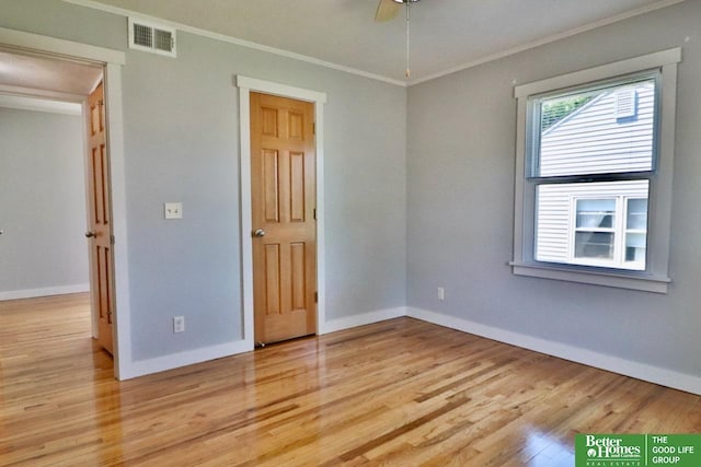 empty room with ornamental molding, light wood finished floors, baseboards, and ceiling fan