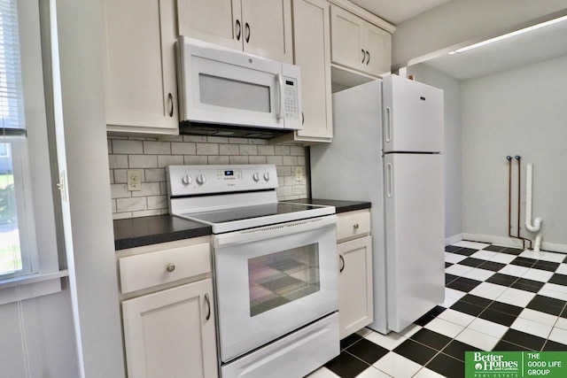 kitchen with white appliances, dark countertops, tasteful backsplash, and white cabinets