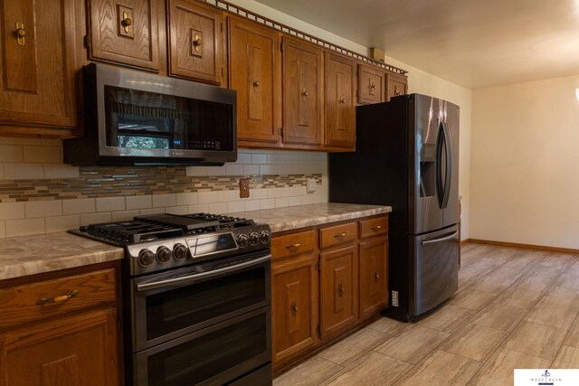 5 Fairview Dr, York, NE 68467 - kitchen with appliances with stainless steel finishes, tasteful backsplash, brown cabinetry, baseboards, and light countertops