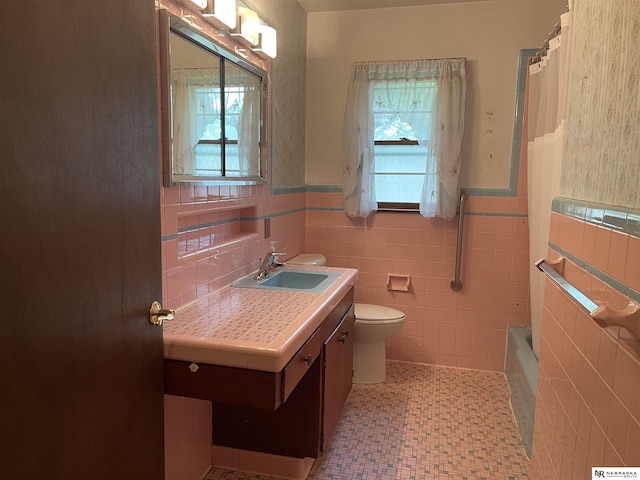 1801 Franklin St, Bellevue, NE 68005 - bathroom with plenty of natural light, toilet, vanity, a wainscoted wall, and tile walls