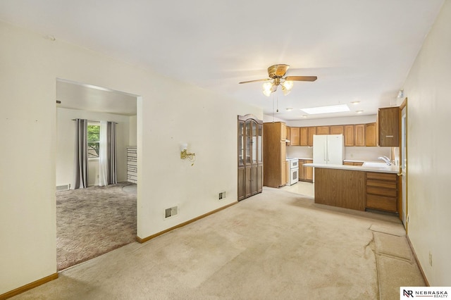 1801 Franklin St, Bellevue, NE 68005 - kitchen with light colored carpet, freestanding refrigerator, brown cabinetry, ceiling fan, and light countertops