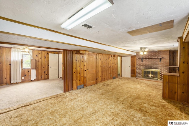 1801 Franklin St, Bellevue, NE 68005 - unfurnished living room with a textured ceiling, ceiling fan, carpet floors, a fireplace, and wood walls