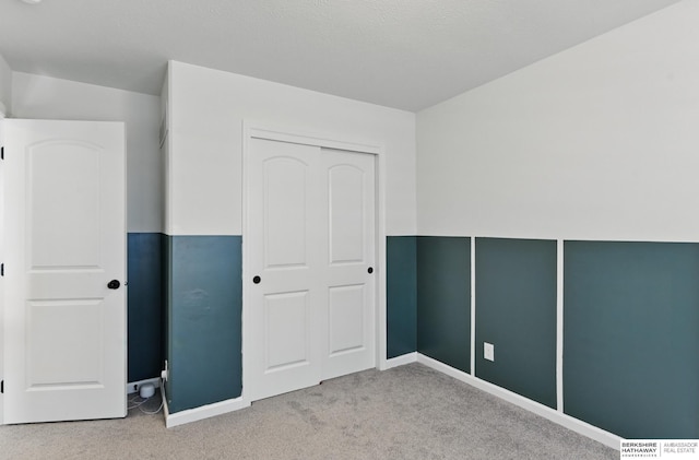 unfurnished bedroom with carpet, baseboards, and a closet