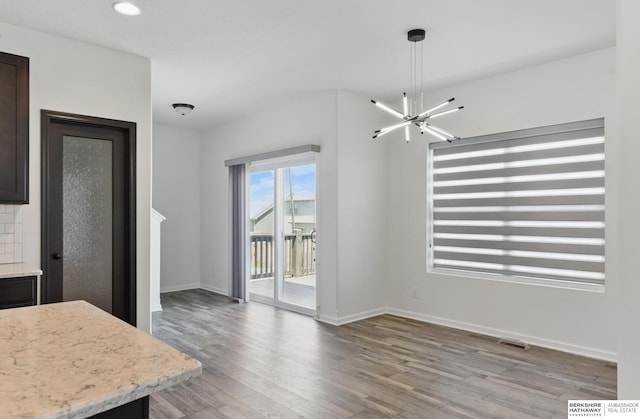 unfurnished dining area with light wood finished floors, baseboards, recessed lighting, and a chandelier