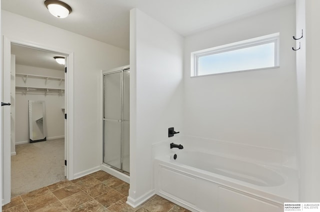 bathroom with a shower stall, a spacious closet, a garden tub, and baseboards