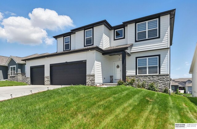 view of front of property featuring stone siding, a front lawn, concrete driveway, and an attached garage