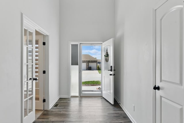 entryway with french doors, dark wood-type flooring, baseboards, and a towering ceiling