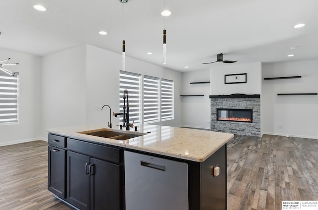 kitchen with a sink, dishwasher, light wood-type flooring, a center island with sink, and recessed lighting