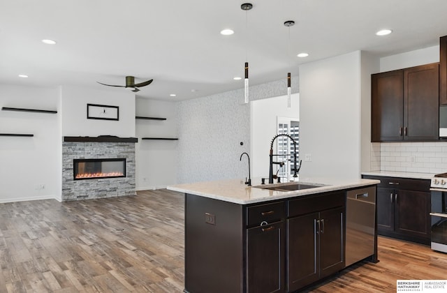 kitchen featuring a sink, dishwasher, electric range oven, light wood-style floors, and open floor plan