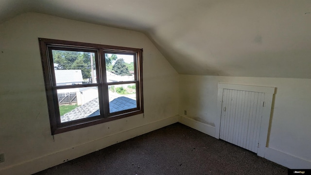 bonus room with lofted ceiling, baseboards, and dark carpet