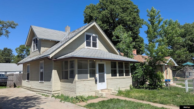bungalow with fence, entry steps, a sunroom, and roof with shingles
