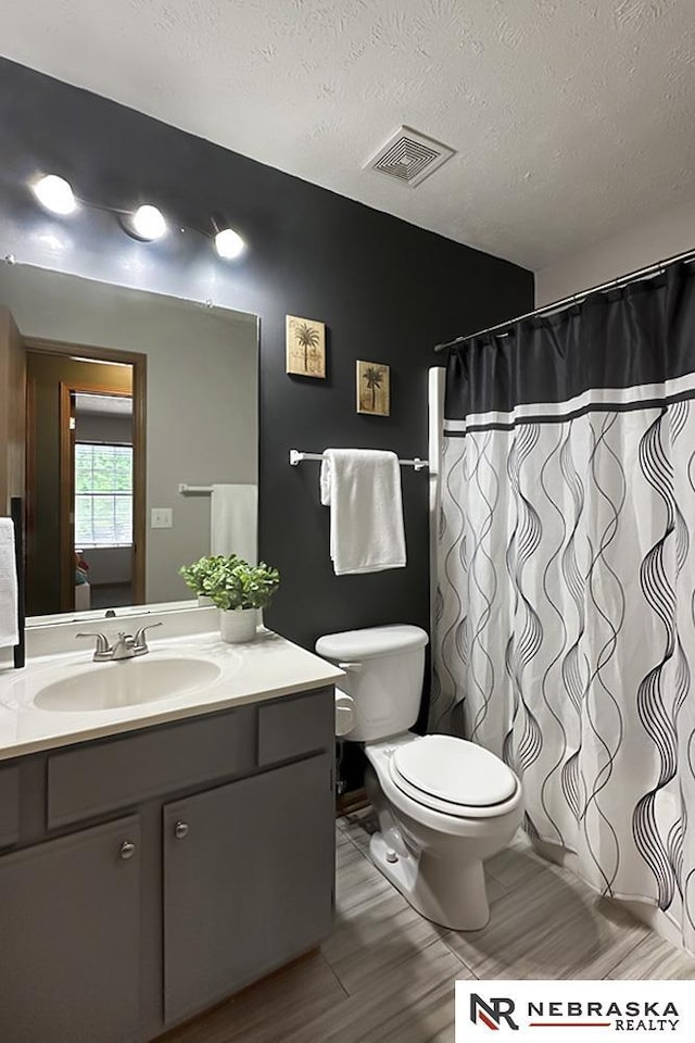 bathroom featuring toilet, vanity, a textured ceiling, wood finished floors, and a shower with curtain
