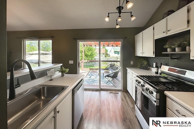 kitchen featuring stainless steel appliances, a sink, wood finished floors, light countertops, and white cabinetry