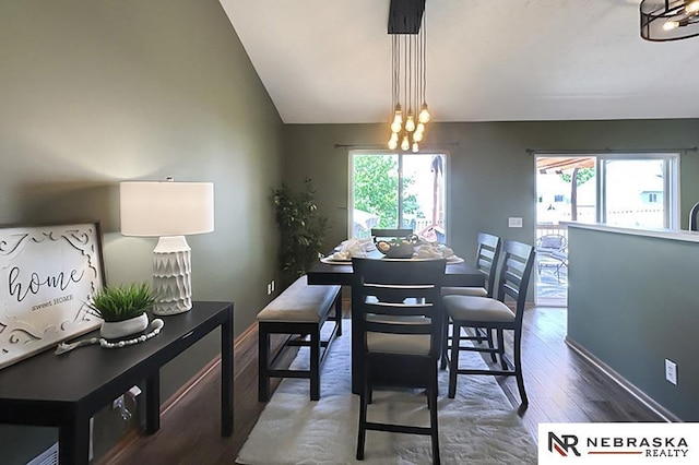 dining room featuring wood finished floors, a chandelier, vaulted ceiling, and baseboards