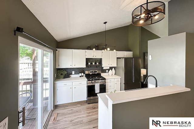kitchen featuring stainless steel appliances, white cabinets, light wood-style flooring, a chandelier, and high vaulted ceiling