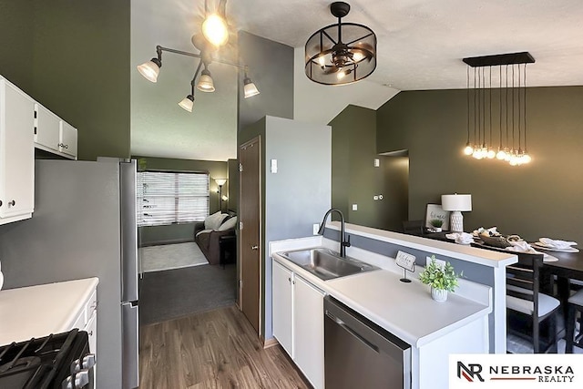 kitchen with stainless steel appliances, a sink, dark wood-type flooring, a peninsula, and light countertops