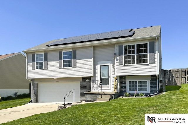 bi-level home featuring concrete driveway, roof mounted solar panels, and an attached garage