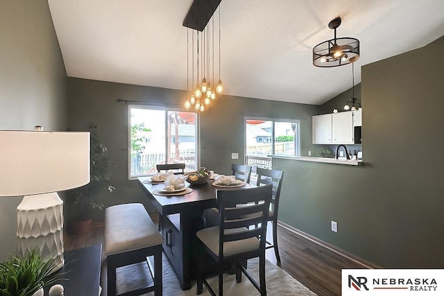 dining area featuring lofted ceiling, a chandelier, wood finished floors, and baseboards