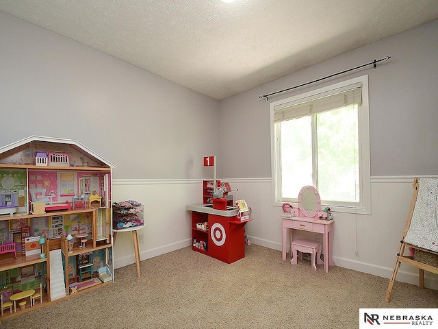 playroom with carpet, wainscoting, and a textured ceiling