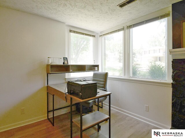 home office with wood finished floors, a textured ceiling, and baseboards