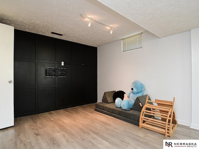sitting room with light wood finished floors, a textured ceiling, and rail lighting